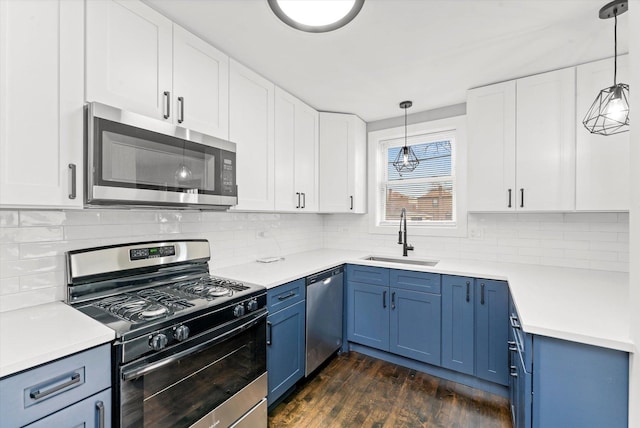 kitchen with hanging light fixtures, appliances with stainless steel finishes, sink, and white cabinets