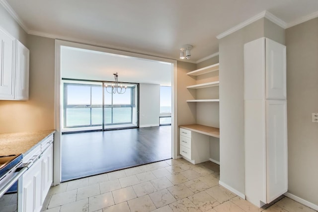 kitchen with white cabinetry, built in desk, electric range, and crown molding