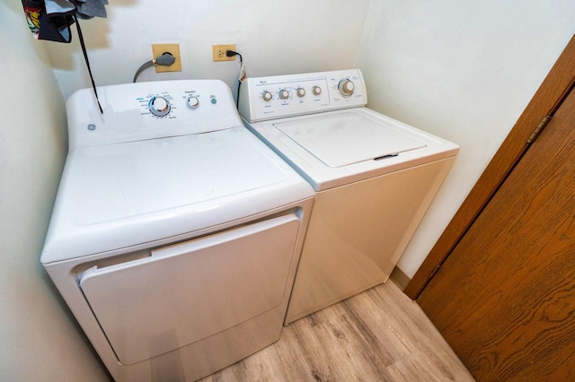 clothes washing area with independent washer and dryer and light hardwood / wood-style floors