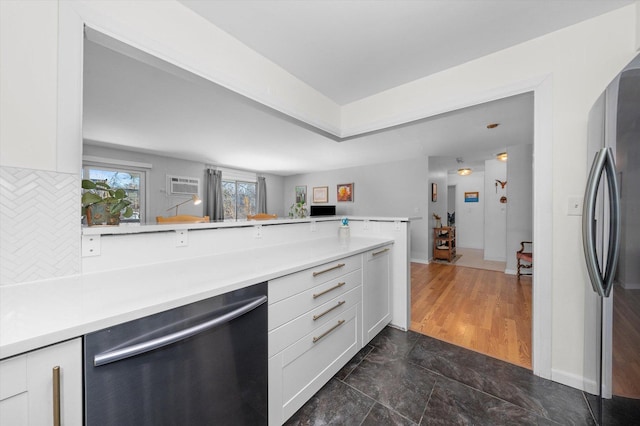 kitchen with backsplash, stainless steel appliances, a wall mounted AC, white cabinets, and kitchen peninsula