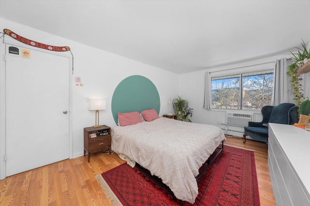 bedroom with an AC wall unit and light hardwood / wood-style floors