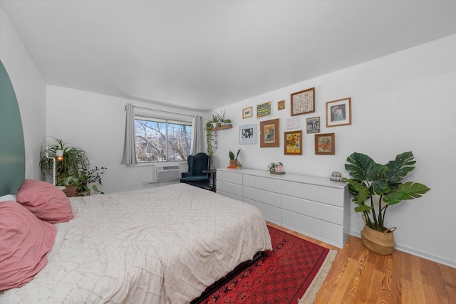 bedroom with cooling unit and light hardwood / wood-style floors