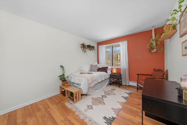 bedroom with wood-type flooring and a baseboard radiator