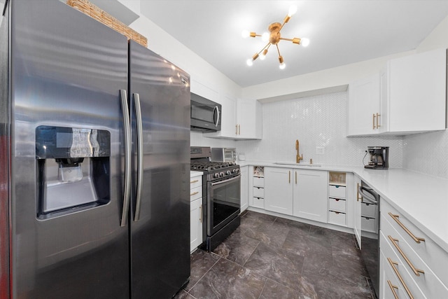 kitchen with appliances with stainless steel finishes, sink, white cabinets, and a chandelier