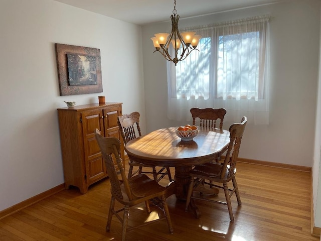 dining area with a notable chandelier, light wood finished floors, and baseboards