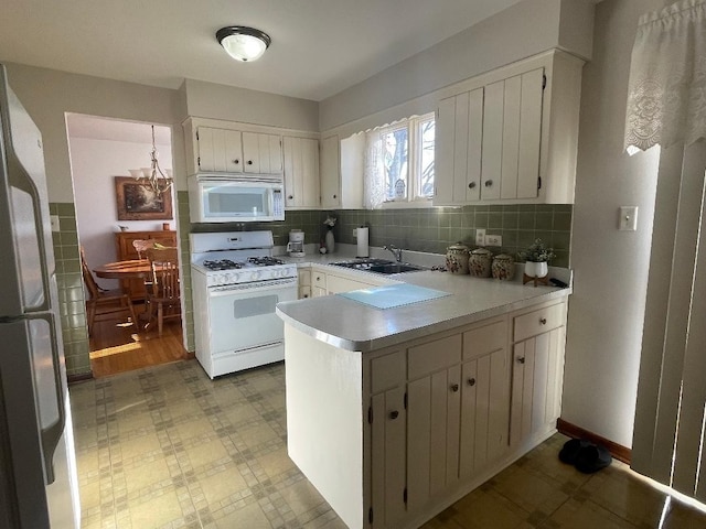 kitchen with white appliances, a sink, white cabinets, light countertops, and tile patterned floors