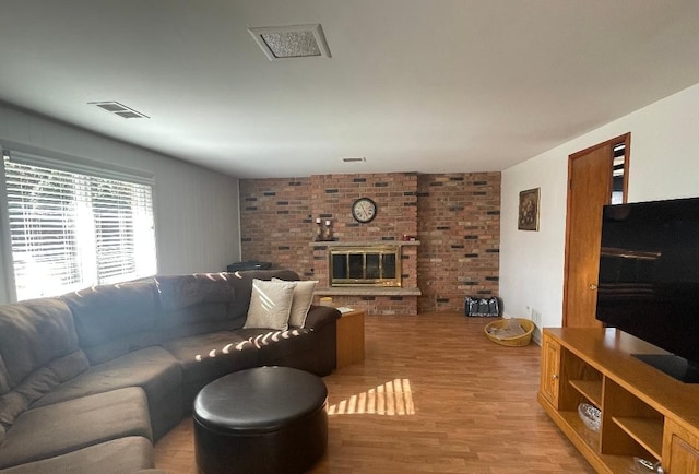 living room featuring a fireplace, visible vents, and light wood-style floors