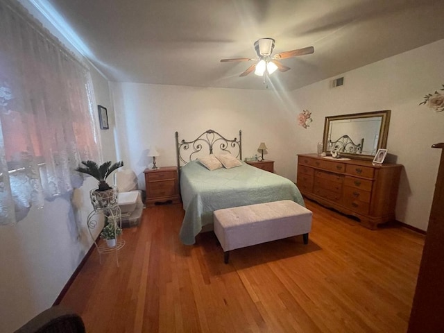 bedroom with a ceiling fan, visible vents, and wood finished floors