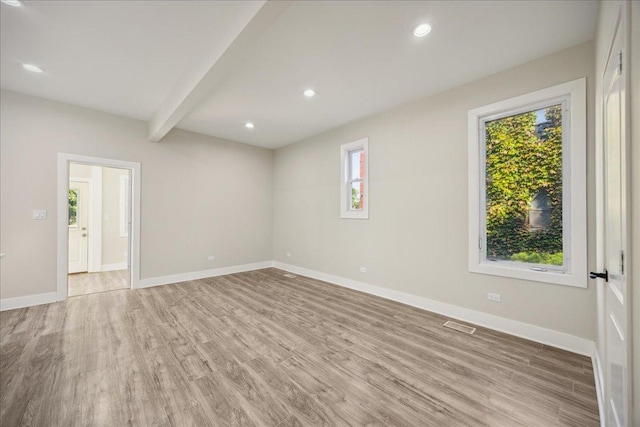 spare room with beam ceiling and light hardwood / wood-style flooring