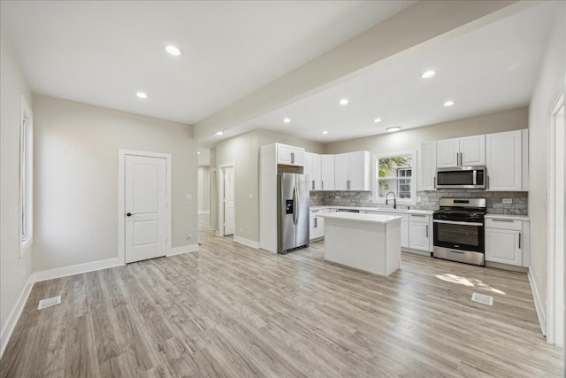 kitchen featuring a kitchen island, white cabinetry, sink, light hardwood / wood-style floors, and stainless steel appliances