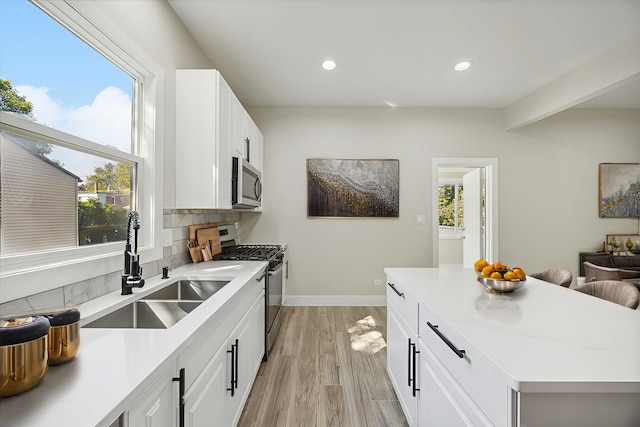 kitchen featuring stainless steel appliances, sink, tasteful backsplash, a healthy amount of sunlight, and white cabinets