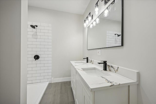 bathroom featuring hardwood / wood-style flooring, vanity, and a tile shower