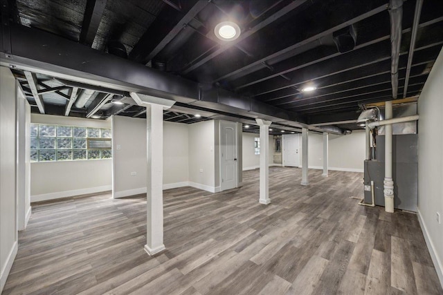 basement with hardwood / wood-style floors and heating unit