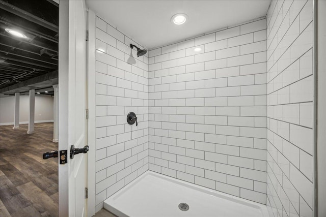 bathroom with a tile shower and hardwood / wood-style flooring