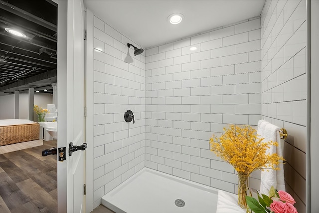 bathroom featuring wood-type flooring and a tile shower