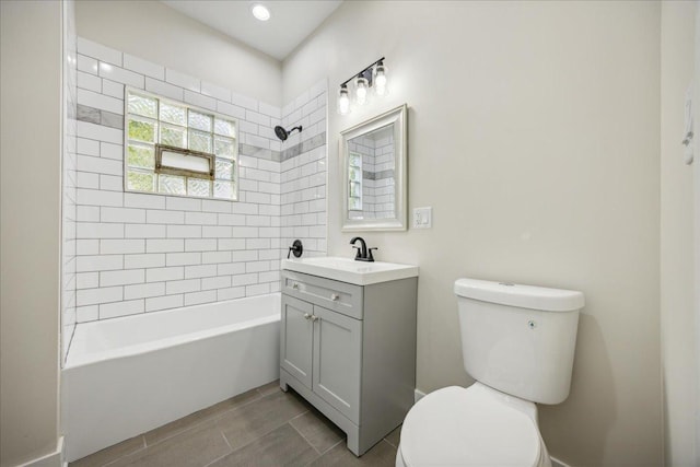 full bathroom featuring tiled shower / bath, vanity, and toilet