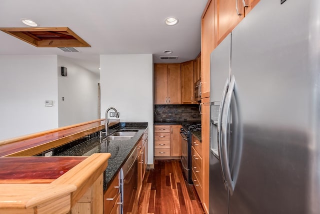 kitchen featuring black gas range oven, sink, stainless steel fridge, tasteful backsplash, and dark hardwood / wood-style flooring