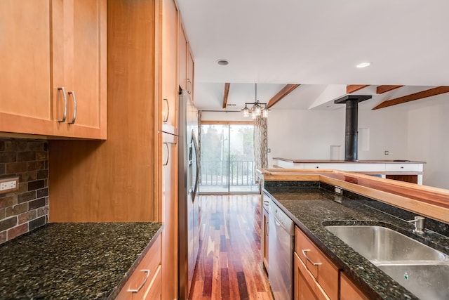 kitchen featuring sink, backsplash, wood-type flooring, and dark stone counters