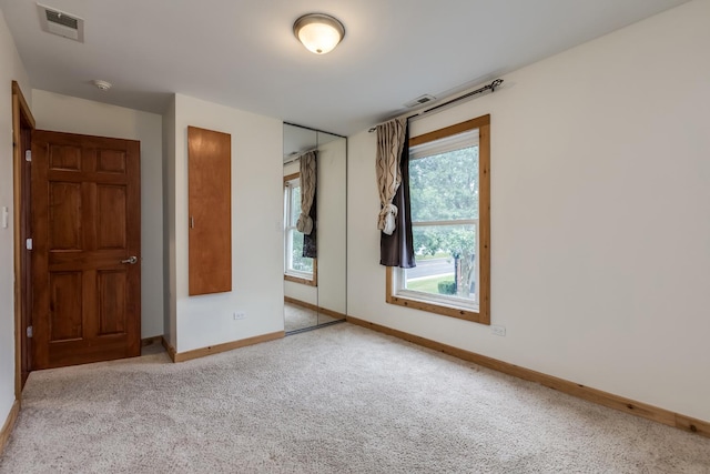 unfurnished bedroom featuring light carpet and a closet