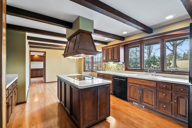 kitchen featuring sink, tasteful backsplash, a center island, light hardwood / wood-style floors, and black appliances