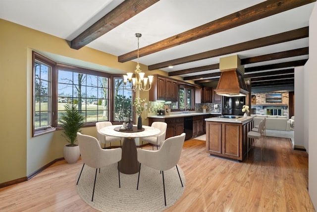 dining area with a notable chandelier, sink, beamed ceiling, and light wood-type flooring