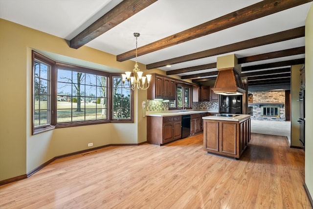 kitchen with a kitchen island, a chandelier, hanging light fixtures, black appliances, and light wood-type flooring