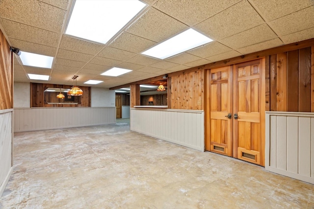 basement featuring a paneled ceiling and wooden walls