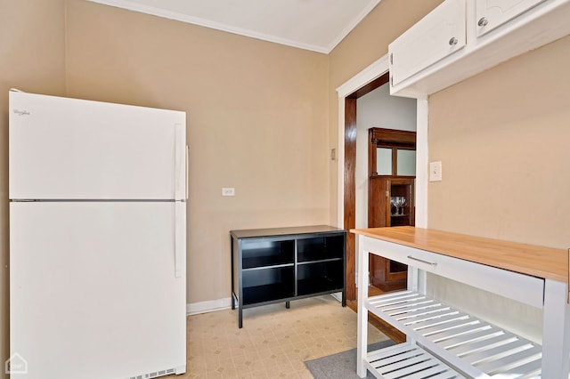 kitchen featuring white cabinetry, crown molding, and white fridge