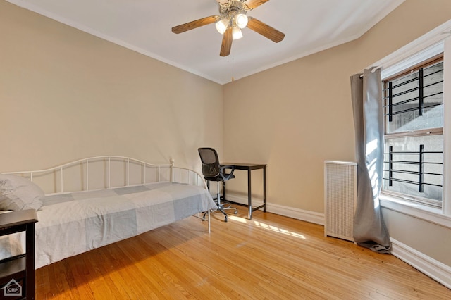 bedroom featuring ceiling fan, wood-type flooring, and ornamental molding