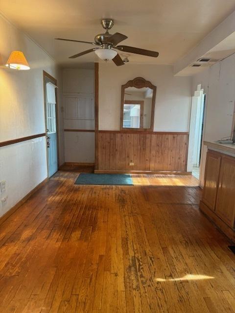 interior space featuring ceiling fan, wooden walls, and light wood-type flooring