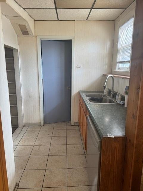 kitchen featuring white dishwasher, sink, a paneled ceiling, and light tile patterned flooring