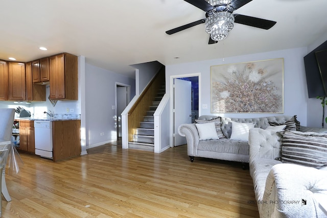 living room featuring ceiling fan, sink, and light wood-type flooring