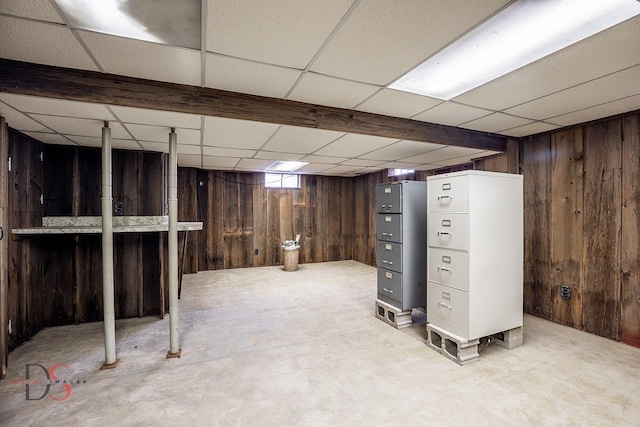 basement with a paneled ceiling and wood walls