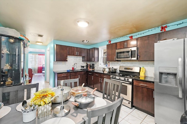 kitchen with sink, dark brown cabinets, stainless steel appliances, and light tile patterned flooring