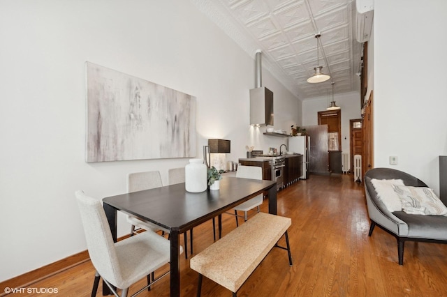 dining space with crown molding, sink, radiator, and hardwood / wood-style floors