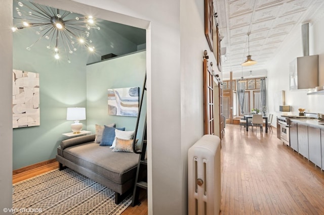 living area with an inviting chandelier, radiator, and light hardwood / wood-style floors