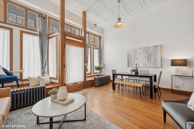 living area with radiator, light hardwood / wood-style flooring, and a high ceiling