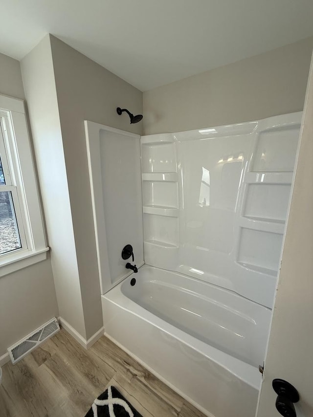 bathroom featuring hardwood / wood-style flooring and washtub / shower combination