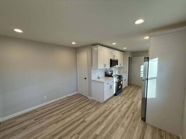 kitchen with white cabinetry, decorative backsplash, stainless steel appliances, and light hardwood / wood-style flooring