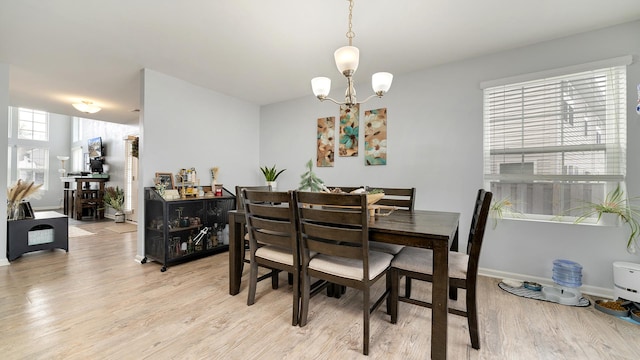 dining space featuring a notable chandelier and light wood-type flooring