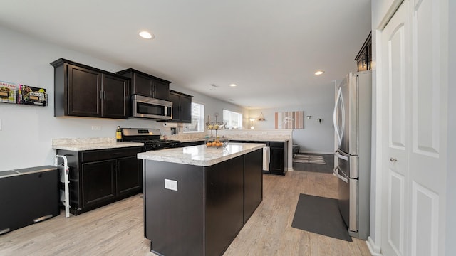 kitchen featuring appliances with stainless steel finishes, kitchen peninsula, a kitchen island, and light hardwood / wood-style flooring