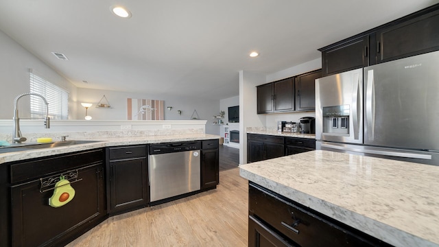 kitchen with appliances with stainless steel finishes, sink, and light wood-type flooring