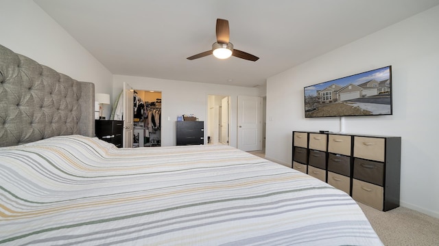 carpeted bedroom featuring a walk in closet, a closet, and ceiling fan