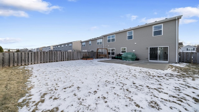 snow covered back of property featuring a patio area