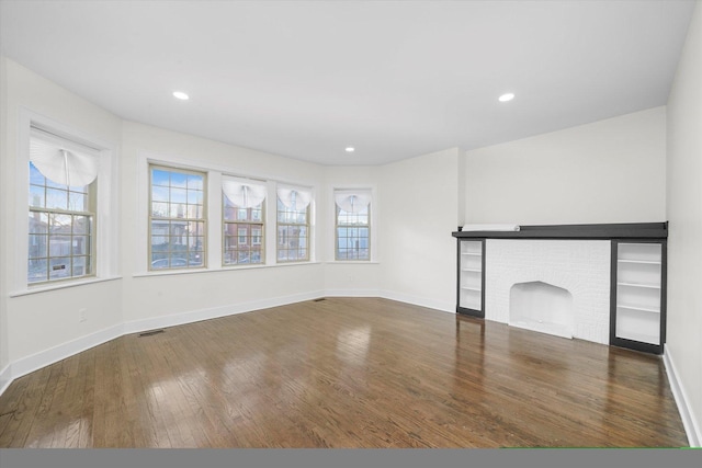 unfurnished living room with dark hardwood / wood-style flooring and a brick fireplace