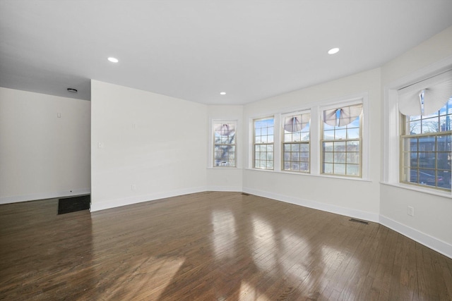 spare room with plenty of natural light and dark wood-type flooring