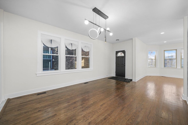 foyer entrance with dark hardwood / wood-style floors and a chandelier