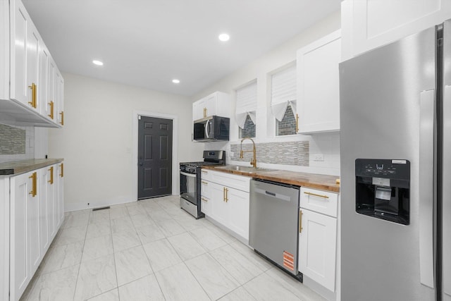 kitchen with white cabinetry, appliances with stainless steel finishes, sink, and wooden counters