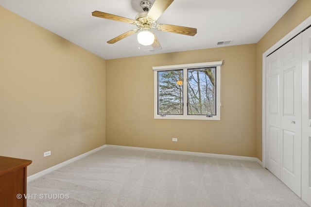 unfurnished bedroom with light colored carpet, a closet, and ceiling fan