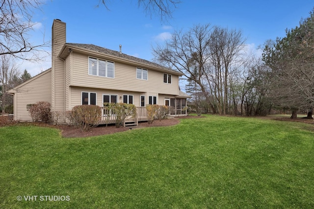 rear view of property featuring a yard, a deck, and a sunroom